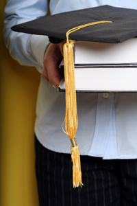 A student with his research books and mortarboard